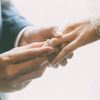 A groom places the wedding ring on the hand of his bride.