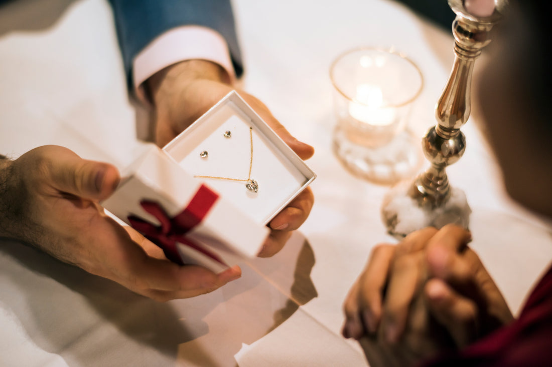 A man gives a woman a heart-shaped necklace and earrings as a Valentine's Day Gift idea. 