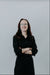 Person wearing glasses and a black outfit against a plain background
