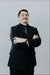 Man in a black suit standing against a plain background