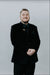 Man wearing a black suit with a bow tie against a white background