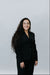 Woman wearing a black suit against a plain background