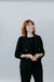 Woman wearing a black blazer against a plain background
